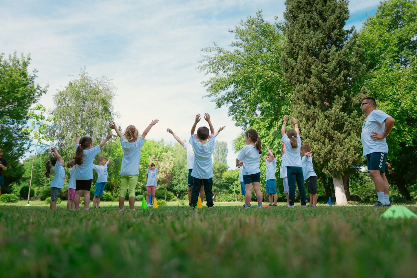 Children and adults participate in an outdoor activity on grass.