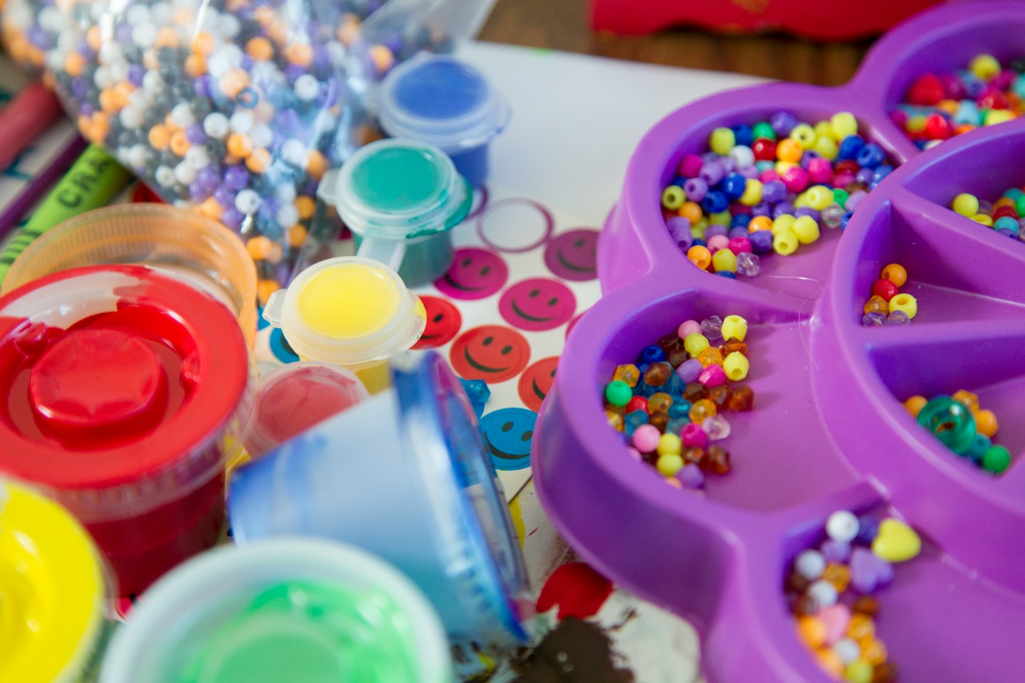 Children's art supplies including paint, beads, and stickers.