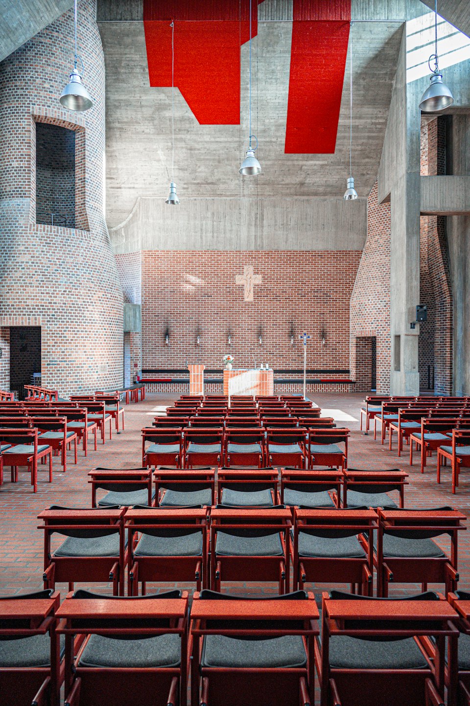 Rows of red chairs face a brick altar in church.