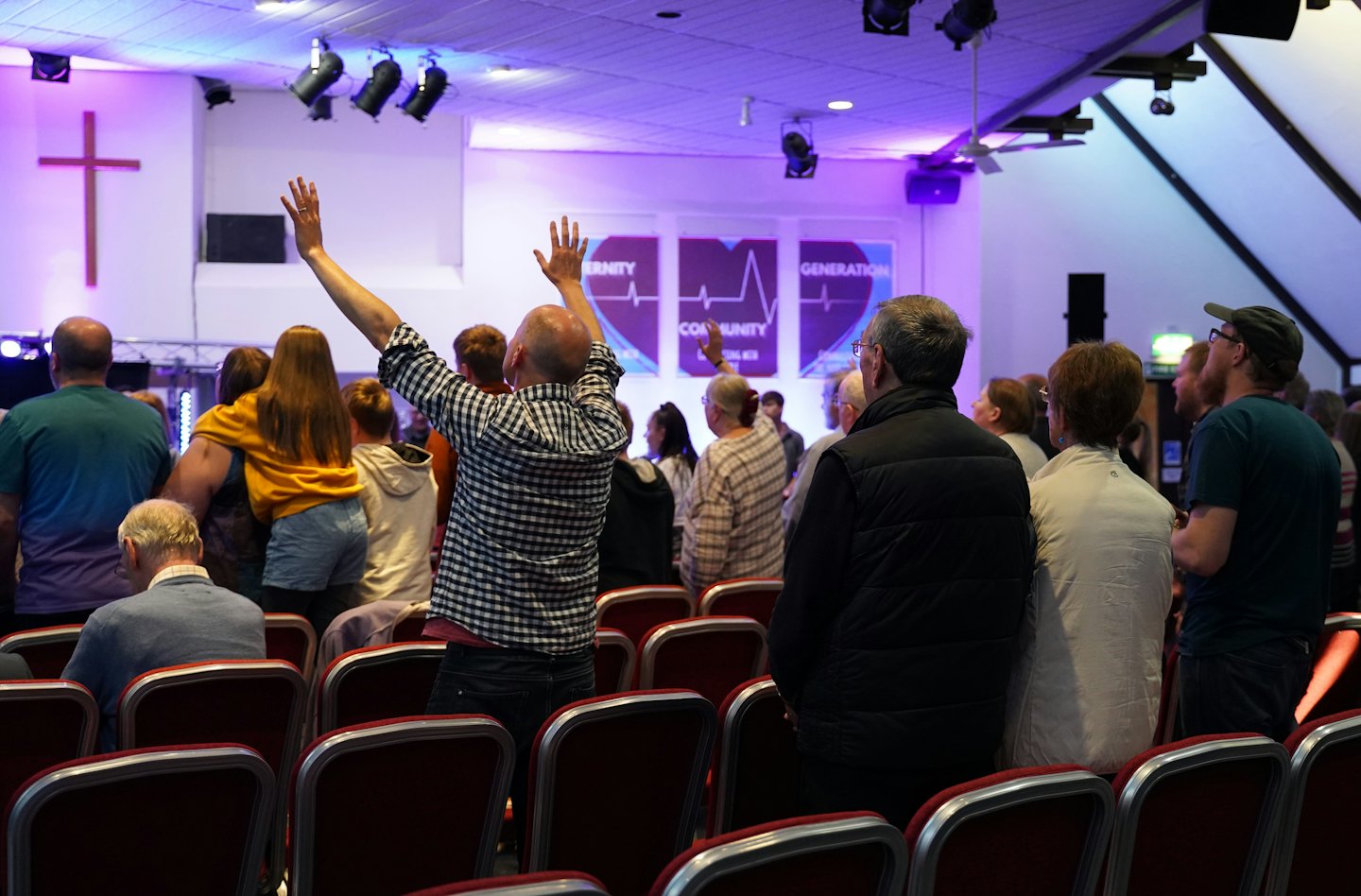 People raise arms in praise during a community service.